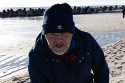 Insel Sylt und Hallig Hooge Oktober 2025 Ein Mann am Strand, umgeben von Wellenbrechern an einem klaren Wintertag. Insel Sylt und Hallig Hooge Oktober 2025 Älterer Mann in Winterkleidung am Strand mit Betonwellenbrechern