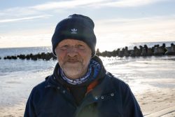 Insel Sylt und Hallig Hooge Oktober 2025 Ein Mann genießt die frische Luft am Strand an einem klaren Wintertag Insel Sylt und Hallig Hooge Oktober 2025 Älterer Mann am sonnigen Strand im Winterkleidung