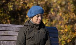 Insel Sylt und Hallig Hooge Oktober 2025 Eine Frau genießt einen sonnigen Herbsttag auf einer Parkbank Insel Sylt und Hallig Hooge Oktober 2025 Frau auf Parkbank mit blauem Barett im Herbst