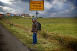 Insel Sylt und Hallig Hooge Oktober 2025 Eine Frau erkundet die malerische und windige Umgebung von Hallig Hooge Insel Sylt und Hallig Hooge Oktober 2025 Frau steht neben Schild auf Hallig Hooge mit windiger Landschaft