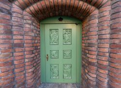 Lüneburg August 2024 Grüne Holztür mit geschnitzten Figuren in Backsteinwand