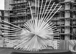 Mainz Street Fotografie Eine beeindruckende Skulptur, die vor einem Gebäude mit Baugerüsten zu sehen ist Mainz Street Fotografie Moderne Skulptur vor einem eingerüsteten Gebäude, abstrakte Strahlenform