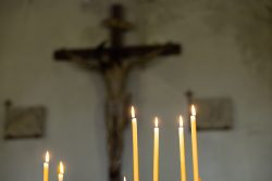 Padua Entschleunigte Fotografie Oktober 2024 Kerzen vor einem unscharfen Kruzifix in einer Kirche