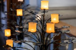 Padua Entschleunigte Fotografie Oktober 2024 Nahaufnahme von brennenden Kerzen auf einem kunstvollen Kerzenständer in einer Kirche