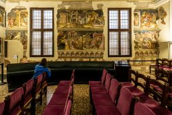 Padua Entschleunigte Fotografie Oktober 2024 Frau betrachtet Fresken in historischer Halle mit lila Stühlen