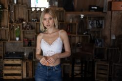 Portraitfotografie Available Light Frau in weißem Spitzenoberteil vor Holzkistenwand