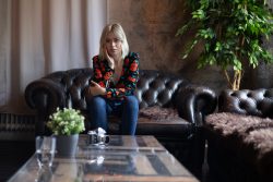 Portraitfotografie Available Light Frau sitzt nachdenklich auf einem Ledersofa in einem stilvoll dekorierten Raum