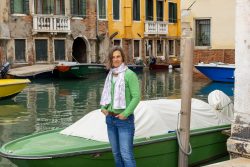 Venedig Entschleunigte Fotografie Oktober 2024 Frau steht vor grünem Boot an Kanal in Venedig