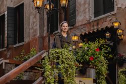 Venedig Entschleunigte Fotografie Oktober 2024 Frau steht auf Treppe vor historischem Gebäude mit Blumenschmuck in Venedig