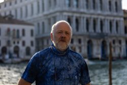 Venedig Entschleunigte Fotografie Oktober 2024 Älterer Mann steht vor historischem Gebäude am Wasser in Venedig