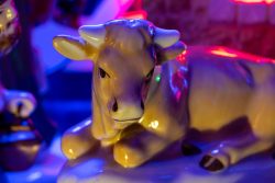 Weihnachtskrippe Villeroy und Boch - Weihnachtsdekoration Keramikfigur einer Kuh mit bunten Lichtern im Hintergrund