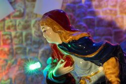 Weihnachtskrippe Villeroy und Boch - Weihnachtsdekoration Bunte Statue einer Frau mit Kapuze vor gemusterter Wand mit Lichteffekten