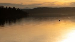 Ammersee Januar 2023 Fotografie Aloys Peter Trenz Ein idyllischer Sonnenuntergangsvollendert den ruhigen Abend über dem See Ammersee Januar 2023 Fotografie Aloys Peter Trenz Sonnenuntergang über ruhigem See mit silhouette der Berge