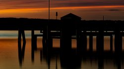 Ammersee Januar 2023 Fotografie Aloys Peter Trenz Ein ruhiger Sonnenuntergang über dem Wasser mit Silhouetten eines Stegs Ammersee Januar 2023 Fotografie Aloys Peter Trenz Schöne Aussicht auf den Sonnenuntergang über einem ruhigen Gewässer mit Steg