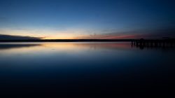 Ammersee Januar 2023 Fotografie Aloys Peter Trenz Ein friedlicher Sonnenuntergang spiegelt sich im ruhigen Wasser eines Sees. Ammersee Januar 2023 Fotografie Aloys Peter Trenz Ruhiger See bei Sonnenuntergang mit farbigem Himmel