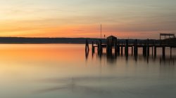 Ammersee Januar 2023 Fotografie Aloys Peter Trenz Ein ruhiger Abendhimmel spiegelt sich im See, während die Sonne sich hinter den Horizont senkt. Ammersee Januar 2023 Fotografie Aloys Peter Trenz Sonnenuntergang über einem ruhigen See mit Steg im Vordergrund