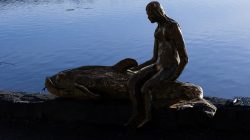 Ammersee Januar 2023 Fotografie Aloys Peter Trenz Bronzestatue anders Gewässer zeigt harmonisches Zusammenspiel von Mensch und Natur Ammersee Januar 2023 Fotografie Aloys Peter Trenz Bronzestatue einer Frau neben einem Fisch an einem ruhigen Gewässer