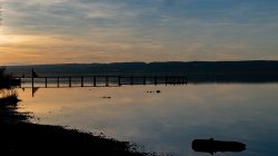 Ammersee Januar 2023 Fotografie Aloys Peter Trenz Ein langer Steg ragt in den ruhigen See bei Sonnenuntergang Ammersee Januar 2023 Fotografie Aloys Peter Trenz Ruhiger See bei Sonnenuntergang mit Steg und Silhouette