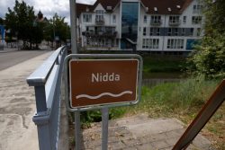 Bad Vilbel Herbst 2022 Fotoserie Aloys Peter Trenz Schild mit der Aufschrift 'Nidda' an einer Brücke in städtischer Umgebung