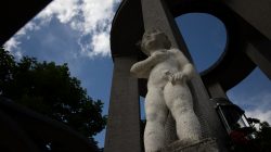 Bad Vilbel Herbst 2022 Fotoserie Aloys Peter Trenz Statue eines Kindes vor einem monumentalen Steinbogen unter blauem Himmel