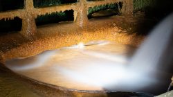 Bad Vilbel Herbst 2022 Fotoserie Aloys Peter Trenz Korrodierter rostiger Wasserkanal mit fließendem Wasser in der Nacht beleuchtet