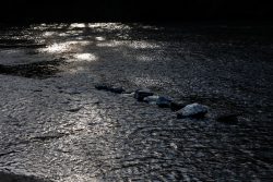 Bad Vilbel Herbst 2022 Fotoserie Aloys Peter Trenz Sonnenstrahlen reflektieren auf einem ruhigen Fluss mit Steinen