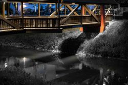 Bad Vilbel Herbst 2022 Fotoserie Aloys Peter Trenz Nachts beleuchtete Holzbrücke über einem ruhigen Fluss