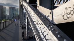 Brücken am Main - Fotoserie Aloys Peter Trenz Industriedenkmal Brücke aus Stahl in urbaner Umgebung mit Skater auf dem Gehweg