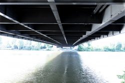 Brücken am Main - Fotoserie Aloys Peter Trenz Unterseite einer Brücke über einen breiten Fluss im grünen Naturumfeld
