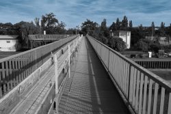 Brücken am Main - Fotoserie Aloys Peter Trenz Langer Fußgängerweg mit Geländern überquert einen Fluss bei Sonnenschein