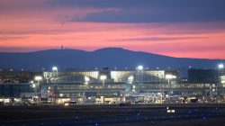 Frankfurt Airport Fotoserie Aloys Peter Trenz Beleuchteter Flughafen Frankfurt bei Sonnenuntergang mit Flugzeugen und Berg im Hintergrund