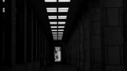 Fotografie Experimente mit Licht und Bewegung August 2022 Dunkler Gebäudekorridor mit geometrischer Beleuchtung und Person im Hintergrund