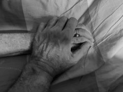 Fotografie Experimente mit Licht und Bewegung August 2022 Zwei ältere Hände halten sich auf einem Bett sanft