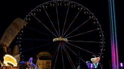 Fotografie Experimente mit Licht und Bewegung August 2022 Beleuchtetes Riesenrad und bunte Jahrmarktstände nachts