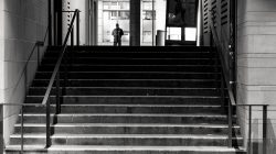 Frankfurt Altstadt und Ostend - Schwarz Weiss Fotografie Ein einzelner Mensch steht am oberen Ende einer Treppe, aufgenommen in Schwarz-Weiß Frankfurt Altstadt und Ostend - Schwarz Weiss Fotografie Schwarz-Weiß-Foto einer Treppe mit entferntem Mensch