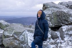 Landschaftsfotografie Großer Feldberg Taunus Winter Januar 2025 Person im Wintermantel auf schneebedecktem Berg mit Felsen