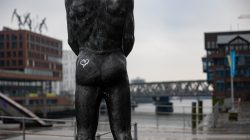 Hamburg Hafencity Fotoserie Aloys Peter Trenz März 2023 Rückansicht einer Statue im Hamburger Hafen mit Brücke im Hintergrund