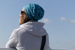 Helgolandreise August 2023 Eine Frau genießt die Aussicht an einem sonnigen Tag Helgolandreise August 2023 Frau mit blauem Schal und Sonnenbrille schaut in den Himmel