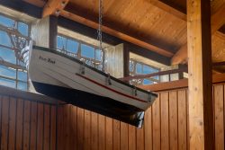 Helgolandreise August 2023 Ein traditionelles Holzboot schwebt dekorativ in einem Raum mit Holzwänden und Sonnenlicht. Helgolandreise August 2023 Holzboot hängt in sonnendurchflutetem Raum an Holzbalkendecke