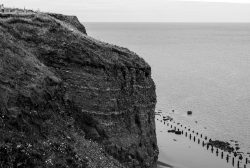 Helgolandreise August 2023 Ein beeindruckendes Küstenkliff ragt über das Meer, eingefangen in Schwarz-Weiß. Helgolandreise August 2023 Schwarz-Weiß-Kliffansicht mit Meer im Hintergrund