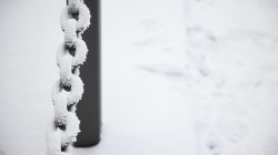 Landschaftsfotografie Winter Gernsheim Dezember 2022 Eine mit Schnee bedeckte Kette hängt neben einem Pfosten im Winterpark Landschaftsfotografie Winter Gernsheim Dezember 2022 Schneebedeckte Metallkette neben einem Pfosten im verschneiten Park