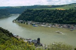 Loreley - Fotoserie - Landschaftsfotografie - Aloys Peter Trenz Rheinlandschaft mit Fluss, Häusern und Hügeln unter wolkigem Himmel