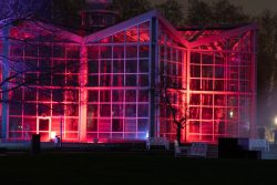 Palmengarten Frankfurt Winterlichter Januar 2022 Gläsernes Gebäude im Park bei Nacht mit roter Beleuchtung
