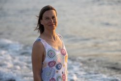 Portraitfotografie Fotoshooting Strand Helgoland August 2024 Frau im bunten Sommerkleid steht am Strand bei Sonnenuntergang