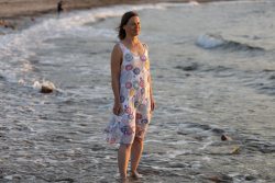 Portraitfotografie Fotoshooting Strand Helgoland August 2024 Frau im Sommerkleid steht barfuß im Meer an einem Sandstrand