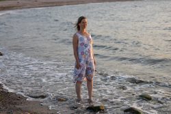 Portraitfotografie Fotoshooting Strand Helgoland August 2024 Frau im Sommerkleid steht am Strand im Abendlicht