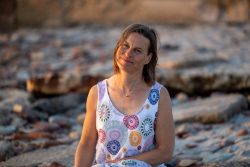Portraitfotografie Fotoshooting Strand Helgoland August 2024 Frau in geblümtem Sommerkleid an einem felsigen Strand