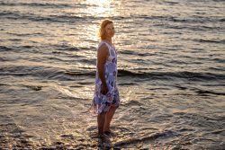 Portraitfotografie Fotoshooting Strand Helgoland August 2024 Frau im Sommerkleid steht bei Sonnenuntergang im Meer