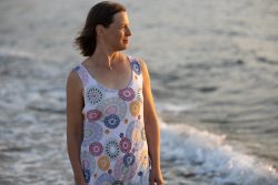 Portraitfotografie Fotoshooting Strand Helgoland August 2024 Frau im bunten Kleid steht am Meer bei Sonnenuntergang