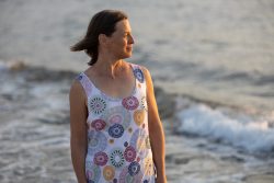 Portraitfotografie Fotoshooting Strand Helgoland August 2024 Frau im gemusterten Kleid steht am Strand bei Sonnenuntergang